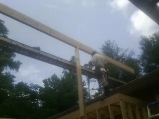 Carpenter setting a ridge beam over a new addition frame — Ice Dam Removal by Roofing Brothers in Houlka