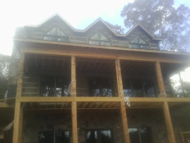 Dormers and porch framing on a large log home under construction — Roof Coating work by our crew in Houlka