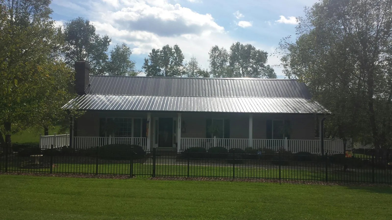 Gray metal roof on a brick ranch with a full width front porch — Gutter Guard Installation work by our crew in Houlka